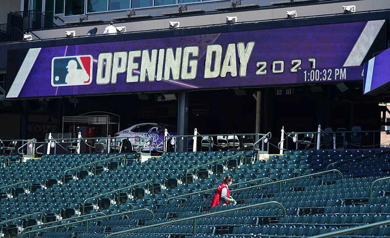 A worker cleans seats to prepare Coors Field for the return of fans in the era of the coronavirus during a news conference Wednesday, March 31, 2021, at the stadium in downtown Denver. A small number of fans were allowed to watch the Rockies go through a workout Wednesday before the team hosts the Los Angeles Dodgers in the squads' season-opener Thursday, April 1. (AP Photo/David Zalubowski)