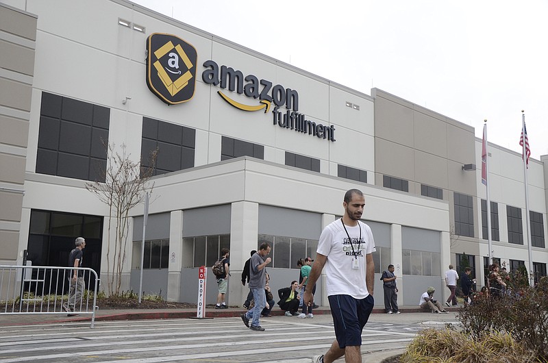 Staff Photo by Logan Foll / The Chattanooga Times Free Press / An Amazon employee walks in front of the Amazon sign while workers take a break at the Amazon Fulfillment Center in the Enterprise South Industrial Park in Chattanooga in 2014.