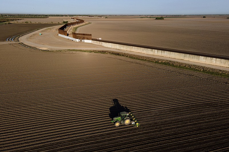 Photo by Julio Cortez of The Associated Press / In this photo taken by a drone, the border wall construction is seen near farmland as a tractor plows a field on Friday, March 19, 2021, in Progerso, Mexico.