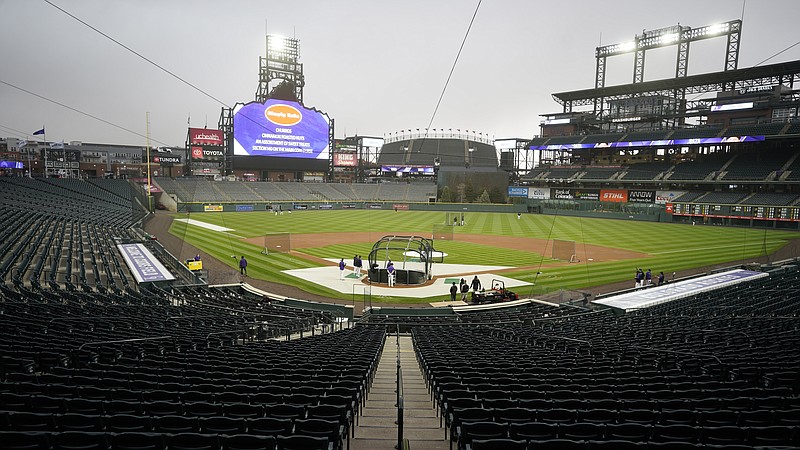 Players take part in batting practice as a light rain descends Tuesday on Coors Field before the Colorado Rockies host the Arizona Diamondbacks.