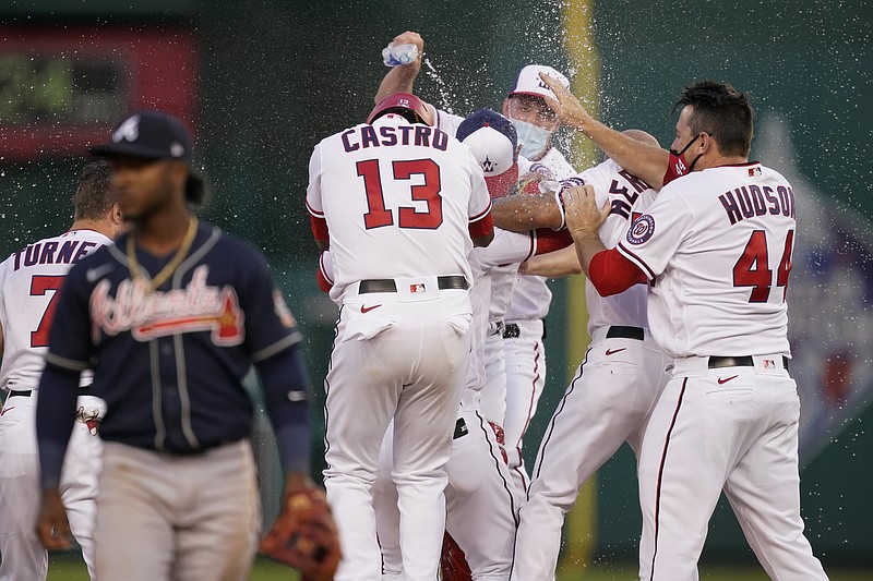 Teammates celebrate with Washington Nationals' Juan Soto in front of Atlanta Braves second baseman Ozzie Albies after Soto hit a game-winning single in the ninth inning of an opening day baseball game at Nationals Park, Tuesday, April 6, 2021, in Washington. Victor Robles scored on the play, and Washington won 6-5. (AP Photo/Alex Brandon)