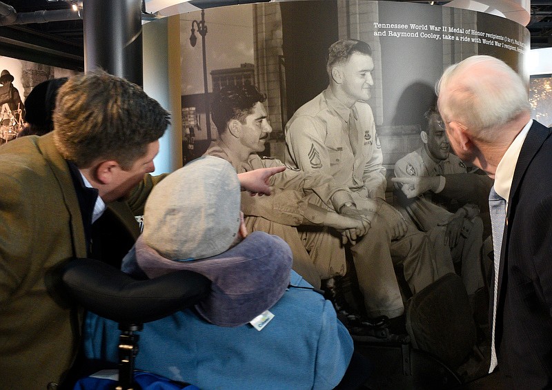 Staff Photo by Robin Rudd / J.C. Coolidge, left, draws his grandfather, Charles Coolidge's attention to a photo of himself, sitting highest in a Jeep with fellow Medal of Honor recipients Paul Huff and Raymond Cooley at the Charles H. Coolidge National Medal of Honor Heritage Center.