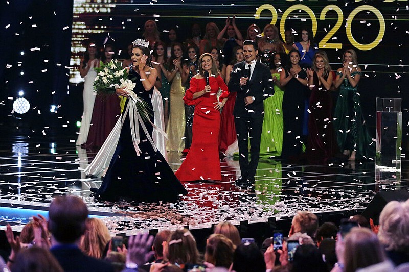 In this Dec. 19, 2019, file photo, Camille Schrier, of Virginia, left, reacts after winning the Miss America competition at the Mohegan Sun casino in Uncasville, Conn. The 100th Miss America will be crowned before a live audience at the Mohegan Sun casino in Connecticut following a year of virtual appearances and postponed competitions due to the pandemic, organizers announced Thursday, April 8, 2021. (AP Photo/Charles Krupa, File)