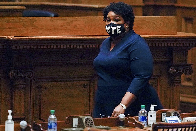 In this Monday, Dec. 14, 2020, file photo, Democrat Stacey Abrams walks on Senate floor before of members of Georgia's Electoral College cast their votes at the state Capitol in Atlanta. In a new interview with The Associated Press, voting rights advocate Abrams discussed a new state law that tightens some Georgia voting rules after Democrats carried the state in the 2020 elections. (AP Photo/John Bazemore, Pool, File)