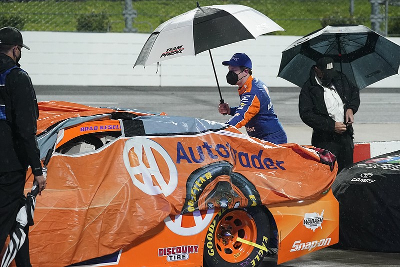 AP photo by Steve Helber / NASCAR Cup Series driver Brad Keselowski, center, helps cover his Team Penske car during a rain delay Saturday night at Virginia's Martinsville Speedway.