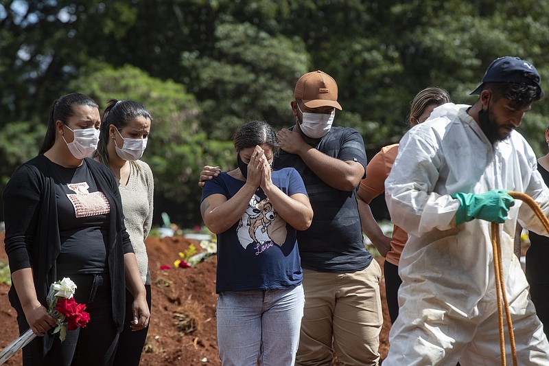 In this April 7, 2021, file photo, people attend the burial of a relative who died from complications related to COVID-19 at the Vila Formosa cemetery in Sao Paulo, Brazil. Nations around the world set new records Thursday, April 8, for COVID-19 deaths and new coronavirus infections, and the disease surged even in some countries that have kept the virus in check. Brazil became just the second country, after the U.S., to report a 24-hour tally of COVID-19 deaths exceeding 4,000. (AP Photo/Andre Penner, File)