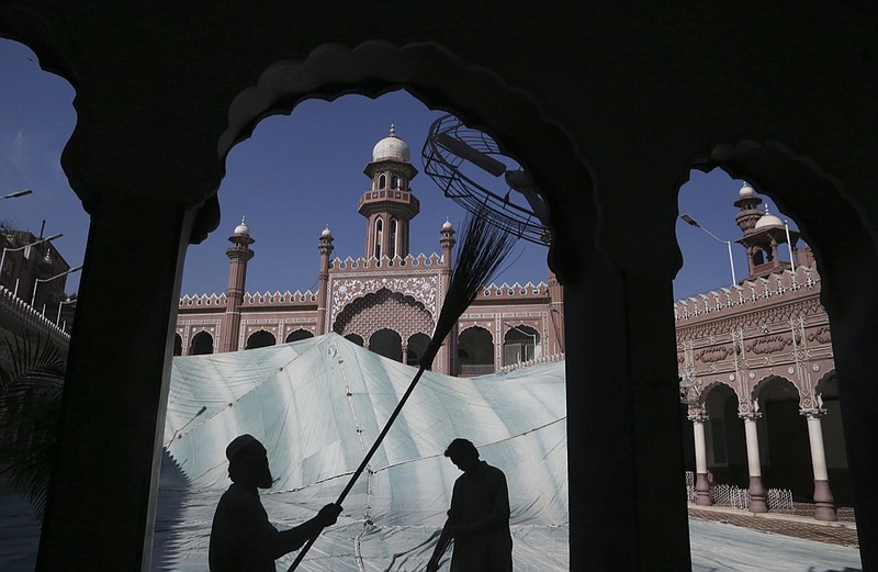 FILE - In this, Friday, April 9, 2021, file photo, volunteers clean the outer areas of the historic Mohabat Khan Mosque ahead of the upcoming Muslim fasting month of Ramadan, in Peshawar, Pakistan. Muslims are facing their second Ramadan in the shadow of the pandemic. Many Muslim majority countries have been hit by an intense new coronavirus wave. While some countries imposed new Ramadan restrictions, concern is high that the month's rituals could stoke a further surge. (AP Photo/Muhammad Sajjad, File)