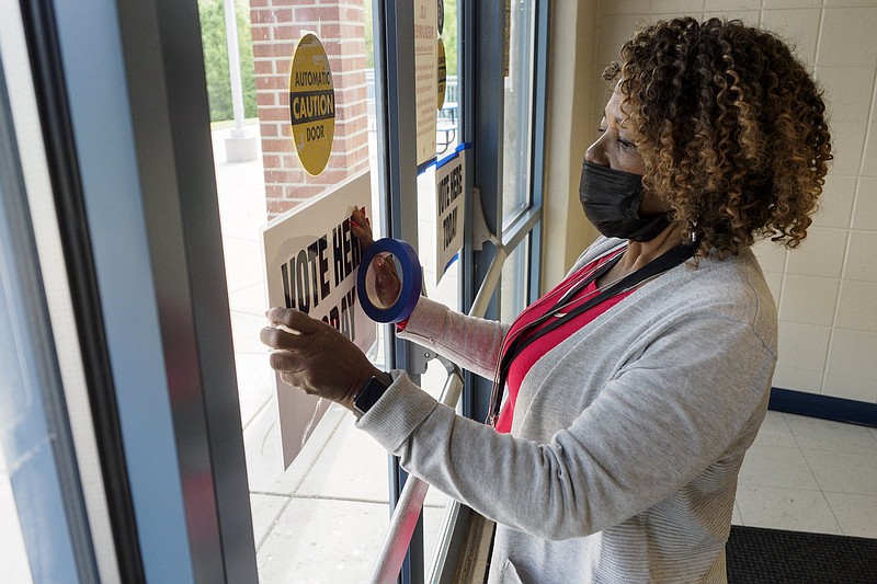 Staff photo by C.B. Schmelter / Gladys Russell, a poll officer, hangs up a "Vote Here Today" sign on election day at the Brainerd Youth and Family Development Center on Tuesday, April 13, 2021 in Chattanooga, Tenn.
