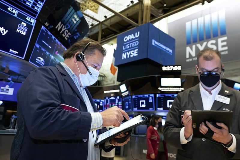 In this photo provided by the New York Stock Exchange, traders John Santiago, left, and William Lawrence, work on the trading floor, Tuesday April 13, 2021. Stocks were choppy and mixed in late morning trading Tuesday as a drop in bond yields hurt bank stocks but helped big technology stocks. (Nicole Pereira/New York Stock Exchange via AP)


