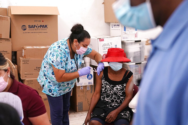 In this April 10, 2021, file photo, registered nurse Ashleigh Velasco, left, administers the Johnson & Johnson COVID-19 vaccine to Rosemene Lordeus, right, at a clinic held by Healthcare Network in Immokalee, Fla. With coronavirus shots now in the arms of nearly half of American adults, the parts of the U.S. that are excelling and those that are struggling with vaccinations are starting to look like the nation's political map: deeply divided between red and blue states. (AP Photo/Lynne Sladky, File)