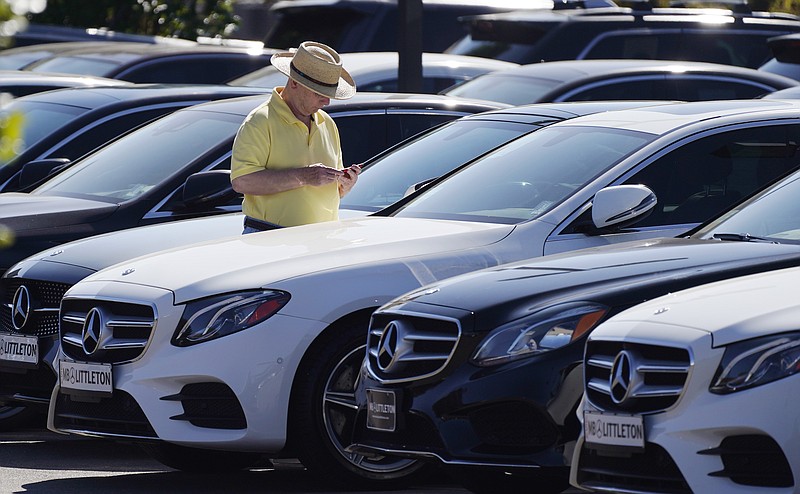 A shopper looks over a long line of 2020 sedans at a Mercedes Benz dealership Sunday, Oct. 4, 2020, in Littleton, Colo. (AP Photo/David Zalubowski)