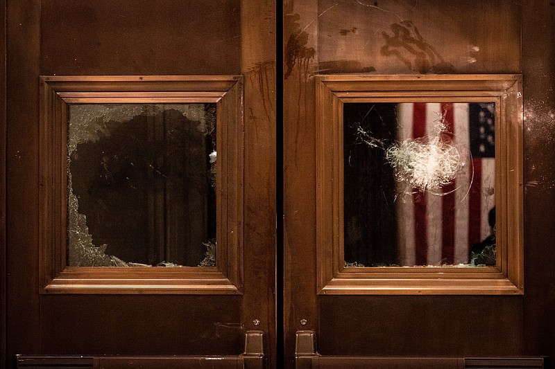 New York Times file photo by Erin Schaff /Broken glass are seen on the doors to the entrance of the Capitol Rotunda in Washington after the Jan. 6 Capitol riot.