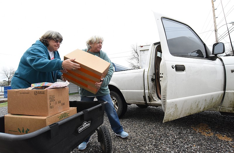 Staff Photo by Matt Hamilton / Elaine Gawthrop, left, and Kendra Phillips place boxes of food into a truck at the Care Mission food pantry in Lafayette, Ga. on Wednesday, March 17, 2021.