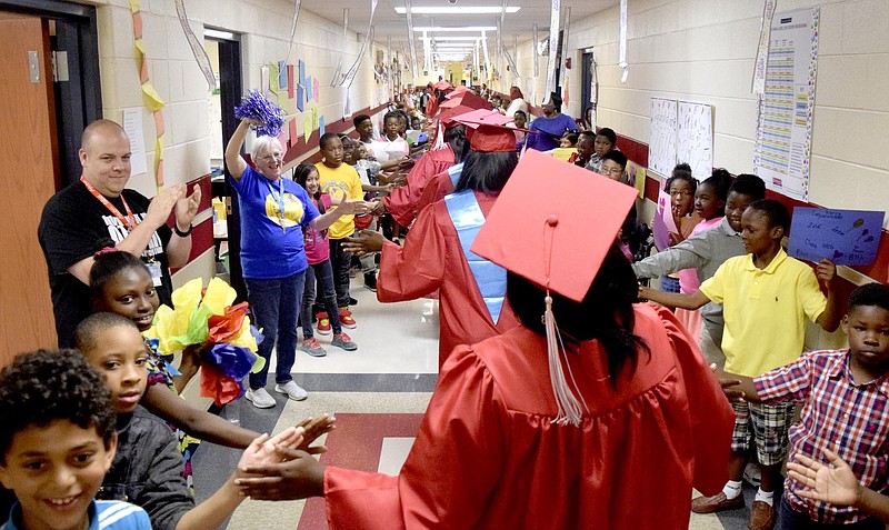 Staff Photo by Robin Rudd | Brainerd seniors process past cheering students on the decorated second floor of Orchard Knob Elementary School. The 2016 graduating class of Brainerd High School walked through the halls of Orchard Knob Elementary in their caps and gowns, as a representation of the "vision" for where the elementary students one day will be.