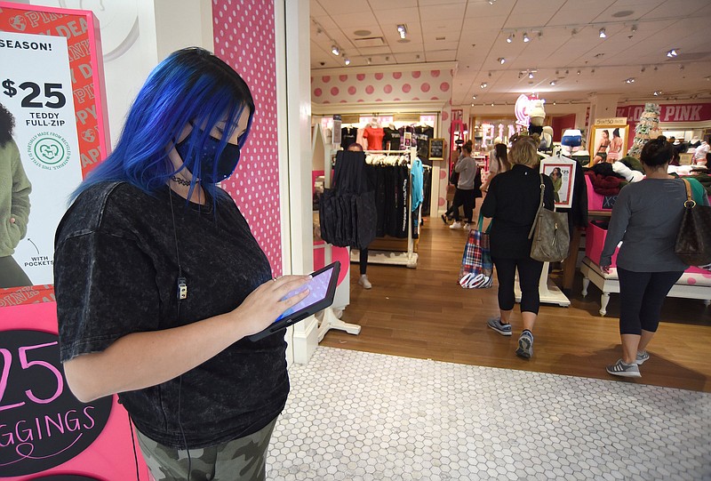 Staff File Photo by Matt Hamilton / Sales representative Casey Newsome keeps track of shoppers entering and exiting Victoria's Secret Pink at Hamilton Place mall recently.