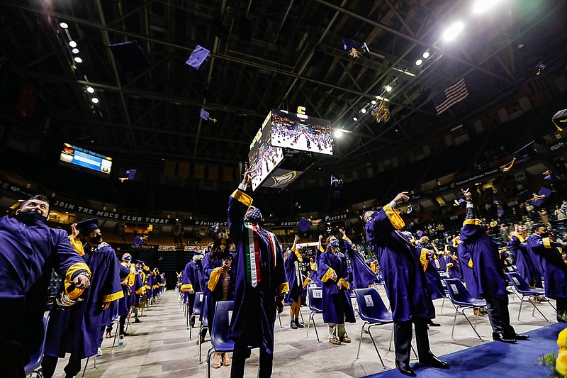 Staff photo by Troy Stolt / Members of the University of Tennessee at Chattanooga class of 2021 throw their caps in the air during one of nine socially distanced graduation ceremonies for the UTC class of 2021 at McKenzie Arena on Friday, April 23, 2021 in Chattanooga, Tenn.