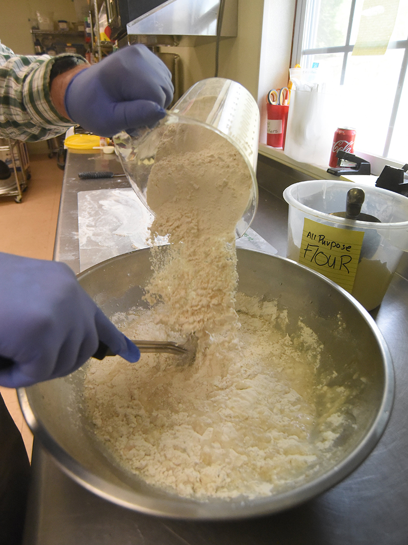 Staff photo by Matt Hamilton / David Rhyne adds flour to his mixing bowl as he makes a loaf of bread at Sunshine Hollow Gardens in Athens, Tenn.