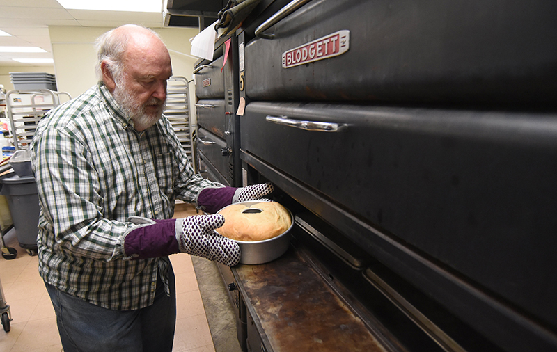 Staff photo by Matt Hamilton / David Rhyne takes a finished loaf of bread from an oven.