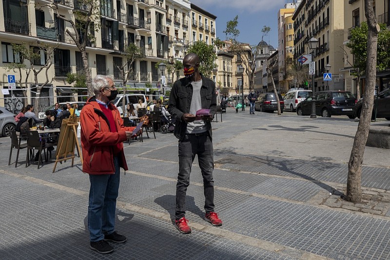 Serigne Mbaye, who is running on a ticket with the anti-austerity United We Can party, in the Madrid regional assembly elections, talks with a potential voter during an election campaign event in Madrid, Spain, Friday, April 16, 2021. Mbaye, a Senegalese-born environmental refugee wants to defy a history of underrepresentation of the Black community and other people of color in Spanish politics. Serigne Mbaye's candidacy has been met with a racist response from an increasingly influential far-right political party. (AP Photo/Bernat Armangue)