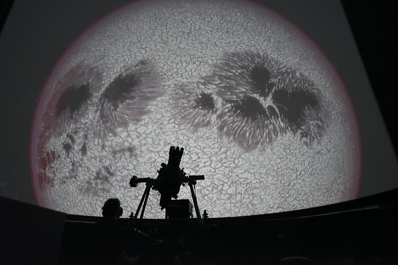Researcher Ivannia Calvo, silhouetted against a solar satellite image, works inside the Solar Astronomical Observatory in San Jose, Costa Rica, Friday, April 30, 2021. Costa Rica approved a law creating a space agency on Feb. 18. (AP Photo/Carlos Gonzalez)