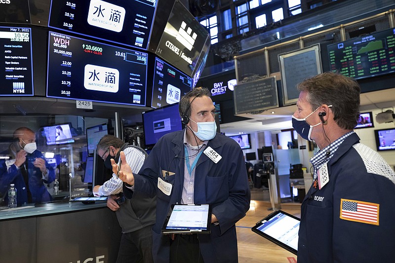 In this photo provided by the New York Stock Exchange, traders Gregory Rowe, center, and Robert Charmak, right, confer on the trading floor, Friday, May 7, 2021. Stocks are rallying to records on Wall Street Friday despite a stunningly disappointing report on the nation's job market, as investors see it helping to keep interest rates low. (Nicole Pereira/New York Stock Exchange via AP)