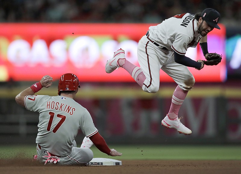 AP photo by Ben Margot / Atlanta Braves shortstop Dansby Swanson, right, hops over Philadelphia Phillies baserunner Rhys Hoskins after completing a double play during the seventh inning of Sunday's NL East matchup at Truist Park in Atlanta.