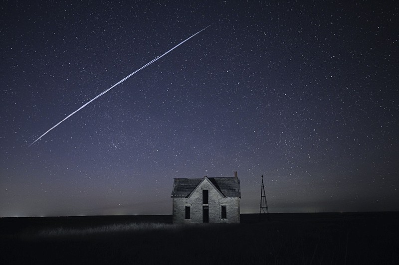 File-In this photo taken May 6, 2021, with a long exposure, a string of SpaceX StarLink satellites passes over an old stone house near Florence, Kan. The train of lights was actually a series of relatively low-flying satellites launched by Elon Musk's SpaceX as part of its Starlink internet service earlier this week. (AP Photo/Reed Hoffmann, File)