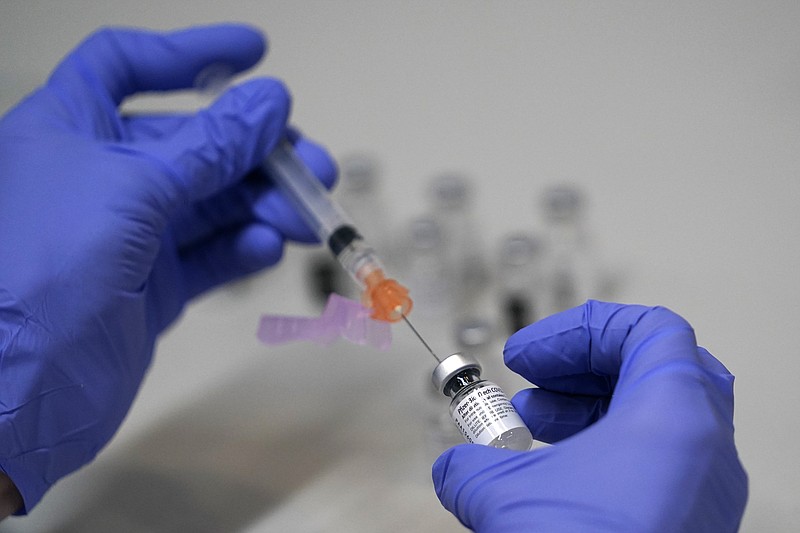 AP file photo by Robert F. Bukaty / A pharmacy technician in Maine loads a syringe with Pfizer's COVID-19 vaccine.