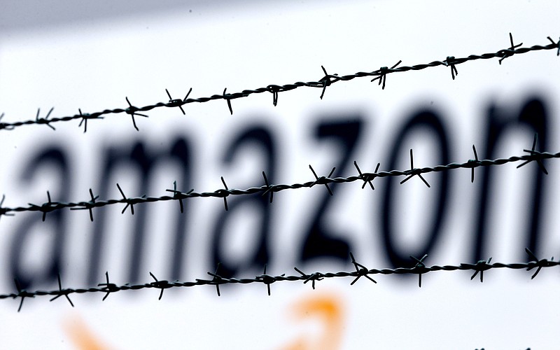 FILE - In this Feb. 19, 2013 file photo, the internet trader Amazon logo is seen behind barbed wire at the company's logistic center in Rheinberg, Germany. A European Union court annulled Wednesday, May 12, 2021 a ruling by the European Commission that a tax deal between the Luxembourg government and Amazon amounted to illegal state support. The Commission's decision related to Luxembourg's tax treatment of two companies in the Amazon group, Amazon EU and Amazon Europe Holding Technologies. (AP Photo/Frank Augstein, File)