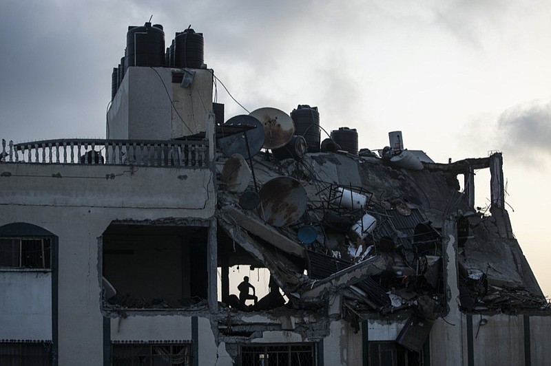 A Palestinian searches for survivors under the rubble of a destroyed rooftop of a residential building which was hit by Israeli missile strikes, at the Shati refugee camp in Gaza City, early Tuesday, May. 11, 2021. (AP Photo/Khalil Hamra)

