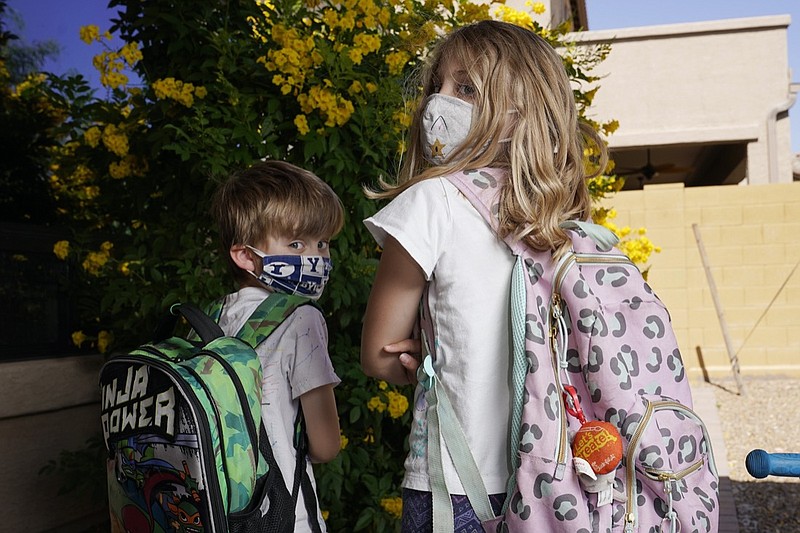 Angela Black, right, with her brother Luke Black at their home, pose for a photo Tuesday, May 11, 2021, in Mesa, Ariz. The students, a third grader and kindergartner, attend a school where mask wearing is optional. (AP Photo/Ross D. Franklin)