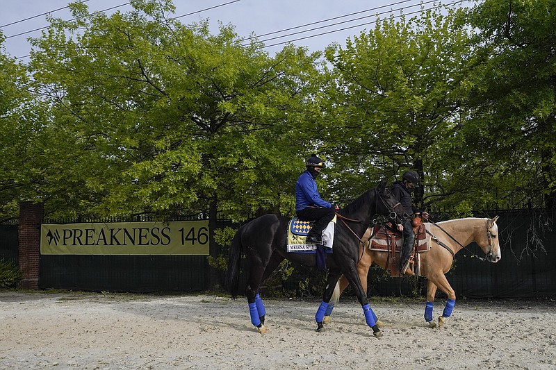 AP photo by Julio Cortez / Exercise rider Humberto Gomez takes Kentucky Derby winner and Preakness Stakes entrant Medina Spirit, left, to the track for a training session Wednesday at Pimlico Race Course in Baltimore.