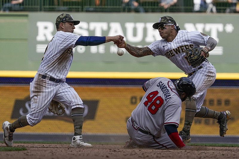 AP photo by Morry Gash / Milwaukee Brewers infielders Luis Urias, left, and Kolten Wong fumble the ball as the Atlanta Braves' Pablo Sandoval slides safely into second base during the seventh inning of Sunday's game in Milwaukee. The Braves scored seven runs in the inning but lost 10-9 as the Brewers avoided being swept in the three-game series.