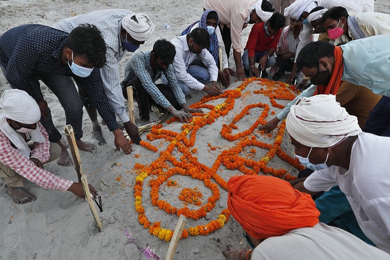 Family members and relatives bow their heads as they pray after burying a person who died of reasons other than COVID-19 in a shallow sand grave on the banks of river Ganges in Prayagraj, India, Sunday, May 16, 2021. Police are reaching out to villagers in northern India to investigate the recovery of bodies buried in shallow sand graves or washing up on the Ganges River banks, prompting speculation on social media that they were the remains of COVID-19 victims. (AP Photo/Rajesh Kumar Singh)