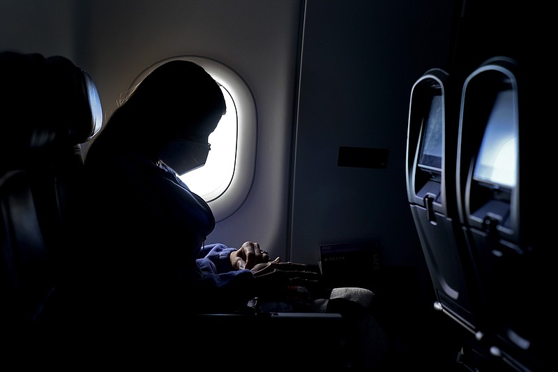 FILE - In this Wednesday, Feb. 3, 2021, file photo, a passenger wears a face mask she travels on a flight from Hartsfield-Jackson International Airport in Atlanta. In May 2021, the Centers for Disease Control and Prevention said people who are fully vaccinated no longer need to wear a mask indoors or outdoors and can stop social distancing in most places. But the CDC says everyone _ vaccinated or unvaccinated _ should continue to wear a mask in certain places. Masks are still required on public transportation _ buses, trains and planes _ and in other settings like hospitals, prisons and homeless shelters. (AP Photo/Charlie Riedel, File)