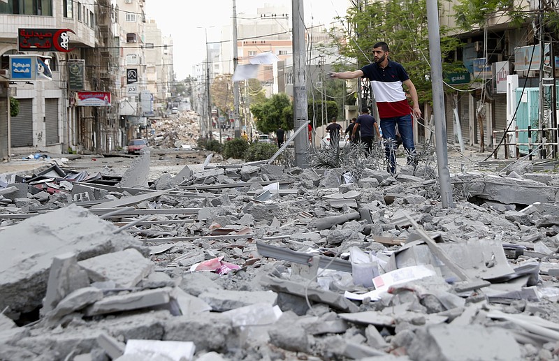 A man inspects the rubble of destroyed commercial building and Gaza health care clinic following an Israeli airstrike on the upper floors of a commercial building near the Health Ministry in Gaza City, on Monday, May 17, 2021. (AP Photo/Adel Hana)