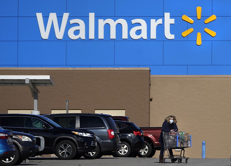 FILE - In this Nov. 18, 2020 file photo, a woman, wearing a protective face mask due to the COVID-19 virus outbreak, wheels a cart with her purchases out of a Walmart store, in Derry, N.H. Walmart Inc. blew past Wall Street projections, reporting strong sales results for the fiscal first quarter as shoppers continued to keep shopping at the discounter even as the pandemic eases. (AP Photo/Charles Krupa, File)