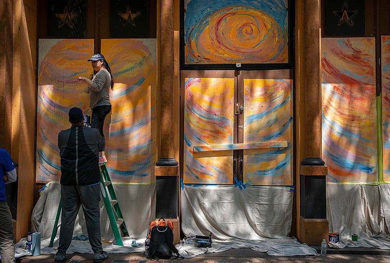 A volunteer paints a boarded up window on Nashville's Second Avenue. Many buildings on the street were heavily damaged by a Christmas Day suicide bomb. (Photo: John Partipilo)