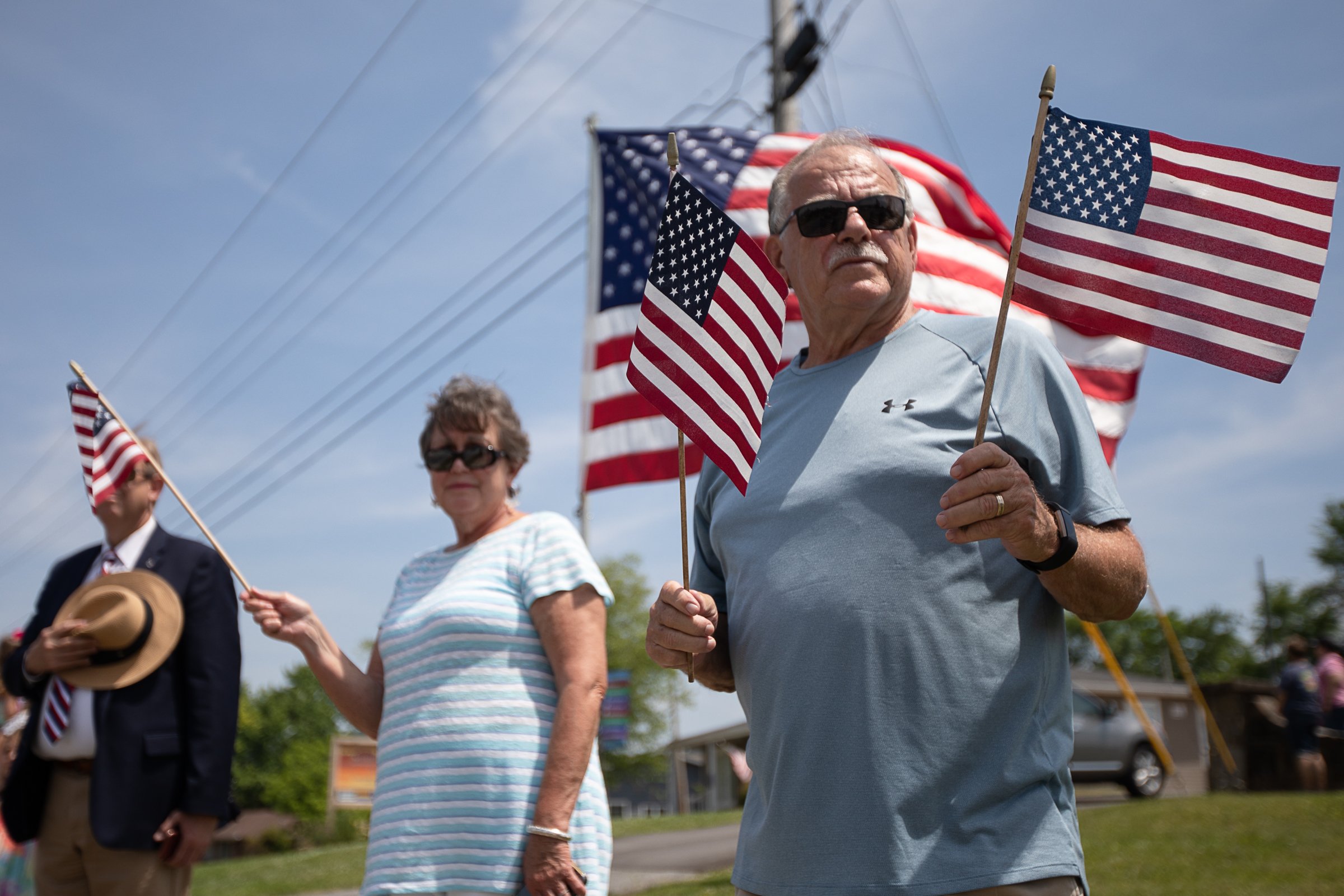 Staff photo by Troy Stolt / Larry Hullander, right, and his wife Carolyn hold flags as they watch a funeral procession for Army Cpl. Henry L. Helms, who was killed in action at The Battle of Chosin Reservoir during the Korean War pull into Anderson Memorial Gardens on Saturday, May 22, 2021 in Ringgold, Georgia. Helms, who was ruled missing in action for seven decades, was identified by his family and given full honors with funeral rites after a 2018 meeting between North Korean Chairman Kim Jong Un and former President Donald Trump, in which an agreement was struck to repatriate remains of Americans collected from the Korean War.