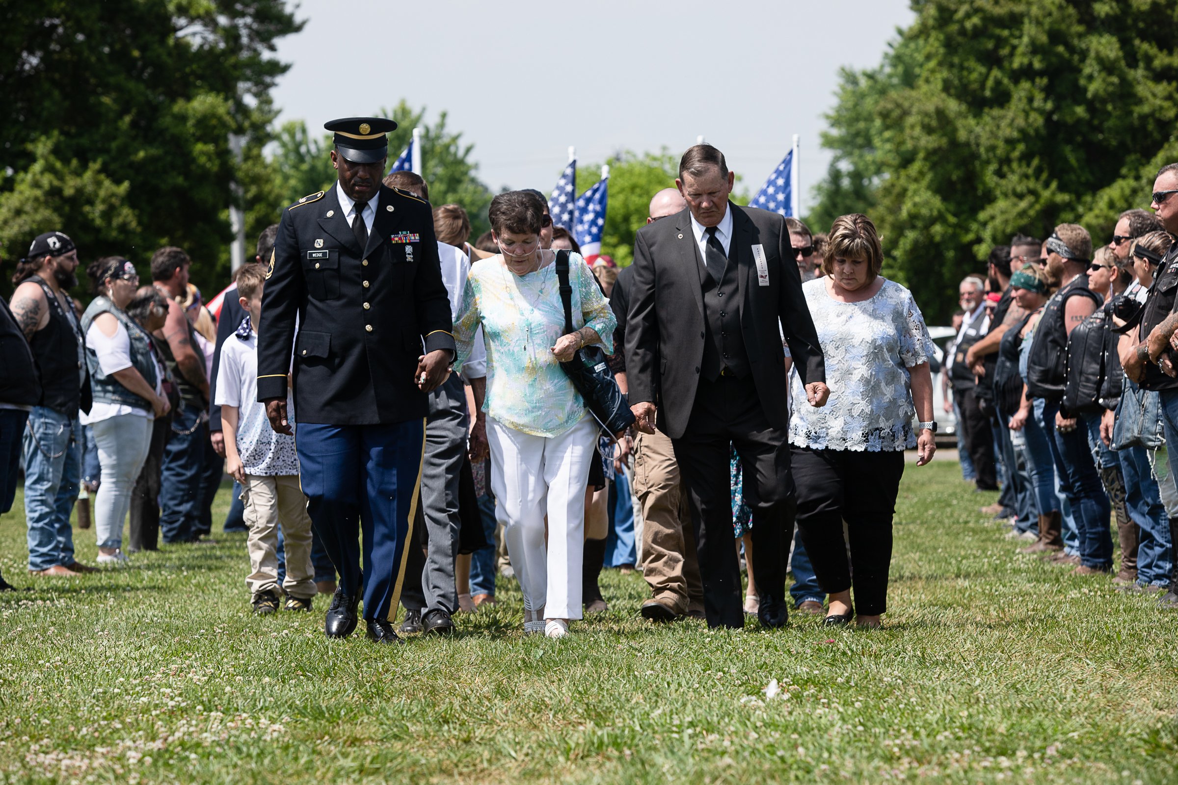 Staff photo by Troy Stolt / Sgt. First Class Kentrate Wedge holds the hand of Evelyn Snyder, the sister of the late Army Cpl. Henry L. Helms, who was killed in action at The Battle of Chosin Reservoir during the Korean War as they walk to a funeral service in Helms' honor on Saturday, May 22, 2021 in Ringgold, Georgia. Helms, who was ruled missing in action for seven decades, was identified by his family and given full honors with funeral rites after a 2018 meeting between North Korean Chairman Kim Jong Un and former President Donald Trump, in which an agreement was struck to repatriate remains of Americans collected from the Korean War.