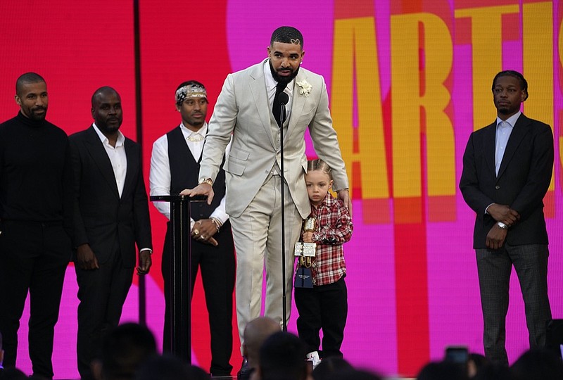 Friends and family look on as Drake accepts the artist of the decade award while he holds his son Adonis Graham at the Billboard Music Awards on Sunday, May 23, 2021, at the Microsoft Theater in Los Angeles. (AP Photo/Chris Pizzello)