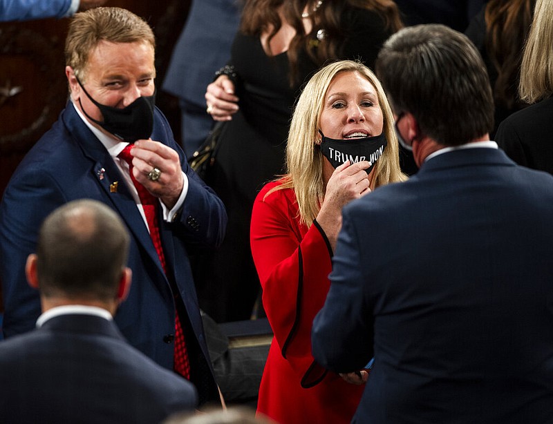 Rep.-elect Marjorie Taylor Greene, R-Ga., pulls down her mask, which reads "Trump won," to speak with a colleague as they await swearing in on the opening day of the 117th Congress at the U.S. Capitol in Washington, Sunday, Jan. 3, 2021. (Bill O'Leary/The Washington Post via AP, Pool)