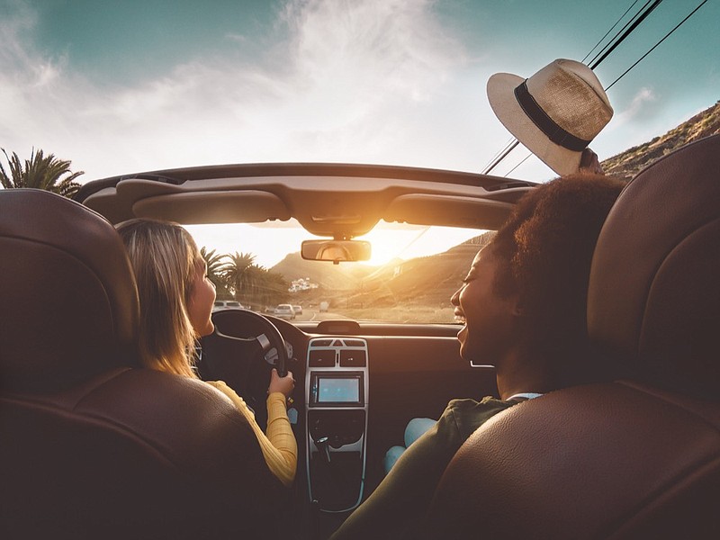 Happy girls doing road trip in tropical city - Travel people having fun driving in trendy convertible car discovering new places - Friendship and youth girlfriends vacation lifestyle concept vacation tile / Getty Images
