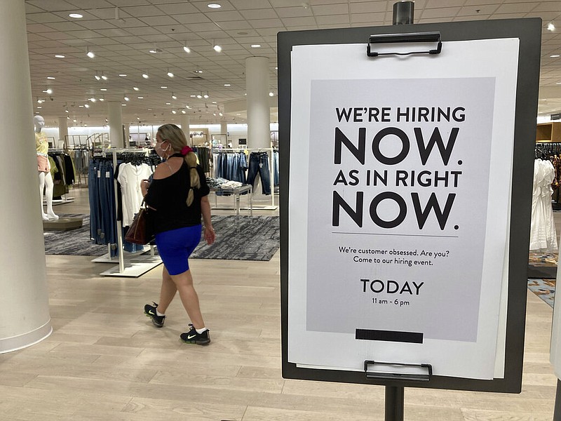 A customer walks behind a sign at a Nordstrom store seeking employees, Friday, May 21, 2021, in Coral Gables, Fla. The number of Americans seeking unemployment benefits dropped last week to 406,000, a new pandemic low and more evidence that the job market is strengthening as the virus wanes and economy further reopens. (AP Photo/Marta Lavandier