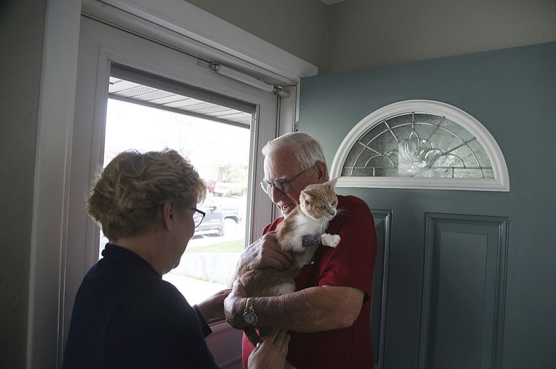 Joan Hepner hands Mitsi the cat over to her owner Norman Shamion in Casper, Wyo., Wednesday May 20, 2021. The cat, a 2-year-old orange and white tabby, disappeared in the middle of a trip from Florida to Casper when she wiggled out of her harness in a Days Inn parking lot. Almost three weeks after Mitsi went missing, she was found. (Cayla Nimmo/The Casper Star-Tribune via AP)


