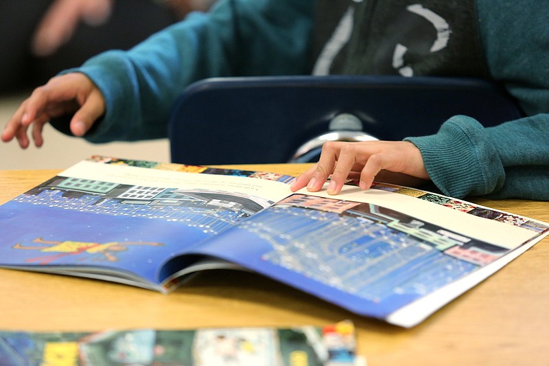 Staff photo by Erin O. Smith / Aaron Perez, 8, flips through the pages of a book he read for book club in Catherine Casselman's class at East Side Elementary Thursday, April 18, 2019 in Chattanooga, Tennessee. Casselman is a second grade teacher at the school who is a graduate of the Public Education Foundation's Project Inspire teaching residency.