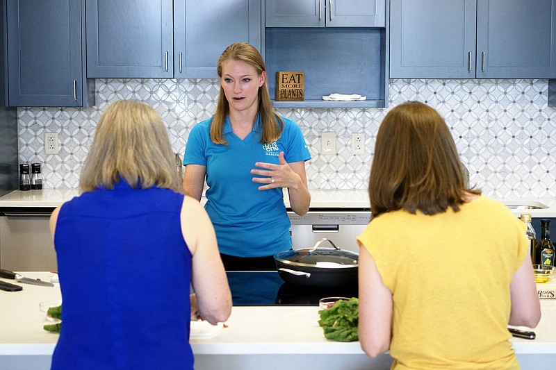 Staff photo by C.B. Schmelter / Health Coach Katie Russell, center, leads a class on using Swiss chard at One to One Health on Thursday, May 27, 2021 in Chattanooga, Tenn.