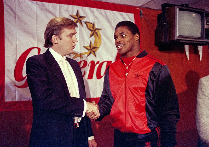 AP photo by Dave Pickoff / New Jersey Generals owner Donald Trump, left, shakes hands with running back Herschel Walker on March 8, 1984, in New York after the University of Georgia star agreed to a four-year contract with the USFL football team. The USFL, which played from 1983 to 1985 before folding, is set to return in spring 2022.