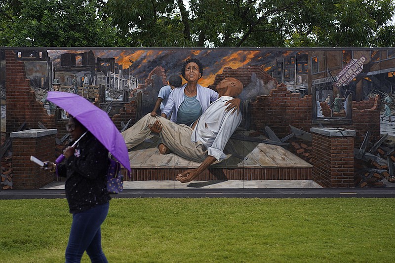 A woman walks by a mural depicting the Tulsa Race Massacre during its centennial, Monday, May 31, 2021, in Tulsa, Okla. (AP Photo/John Locher)