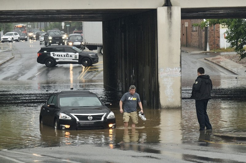 A Chattanooga police officer checks on a stranded driver as they wade out of the deep water at the railroad overpass over E. Main Street on Thursday June 3, 2021. A midday deluge caused several roads to close due to flooding in the area. 

